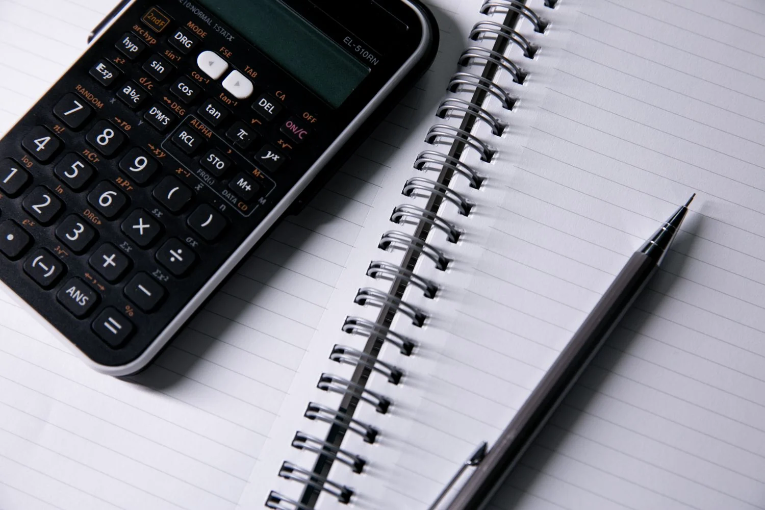 Calculator beside a notebook and pen
